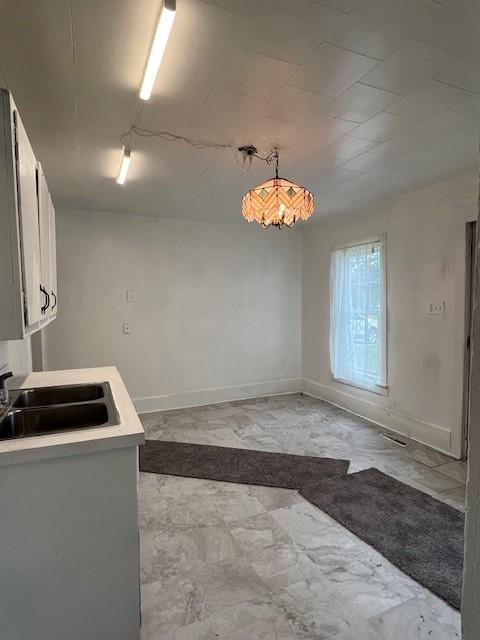 520 S Main St, Stuart, IA 50250 - kitchen with a sink, light countertops, baseboards, and white cabinetry