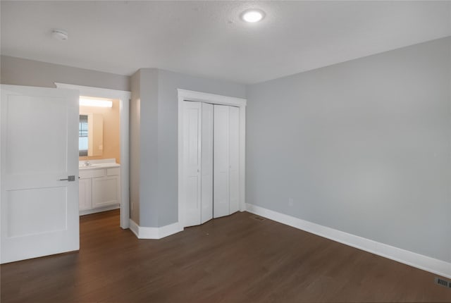 501 Kirkwood Ave, Des Moines, IA 50315 - unfurnished bedroom with dark wood finished floors, baseboards, a sink, and a closet