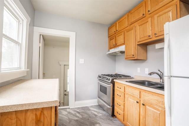 3416 Cambridge St, Des Moines, IA 50313 - kitchen featuring freestanding refrigerator, stainless steel range with gas stovetop, under cabinet range hood, a sink, and light countertops