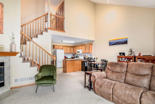 2816 Ashland Ct, Altoona, IA 50009 - living area with a towering ceiling, stairway, a tiled fireplace, and light carpet