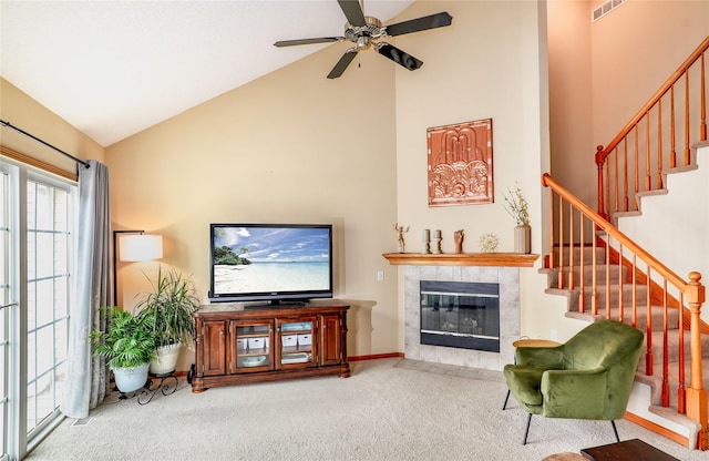 2816 Ashland Ct, Altoona, IA 50009 - carpeted living area with high vaulted ceiling, stairs, a tiled fireplace, and ceiling fan