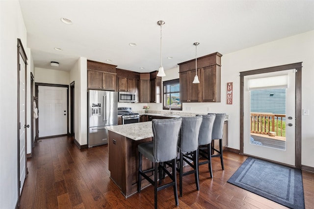 7305 NW 18th St, Ankeny, IA 50023 - kitchen featuring appliances with stainless steel finishes, dark brown cabinets, dark wood-style floors, a kitchen bar, and recessed lighting