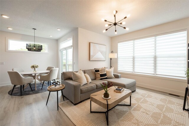523 NE Vista Ln, Ankeny, IA 50021 - living room with a chandelier, light wood-type flooring, baseboards, recessed lighting, and a textured ceiling
