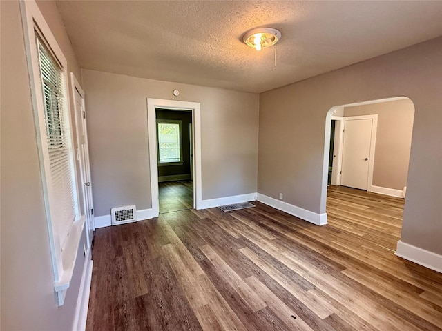 3916 Cambridge St, Des Moines, IA 50313 - spare room featuring arched walkways, a textured ceiling, wood finished floors, and baseboards