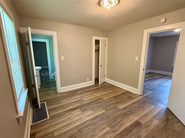 3916 Cambridge St, Des Moines, IA 50313 - unfurnished bedroom with a textured ceiling, dark wood-style flooring, a closet, and baseboards