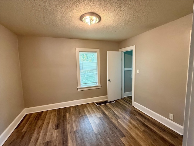 3916 Cambridge St, Des Moines, IA 50313 - spare room with dark wood-style floors, a textured ceiling, and baseboards