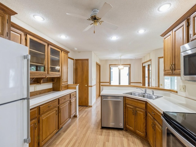 3721 Fletcher Blvd, Ames, IA 50010 - kitchen featuring stainless steel appliances, a textured ceiling, light wood-style floors, brown cabinetry, and a sink