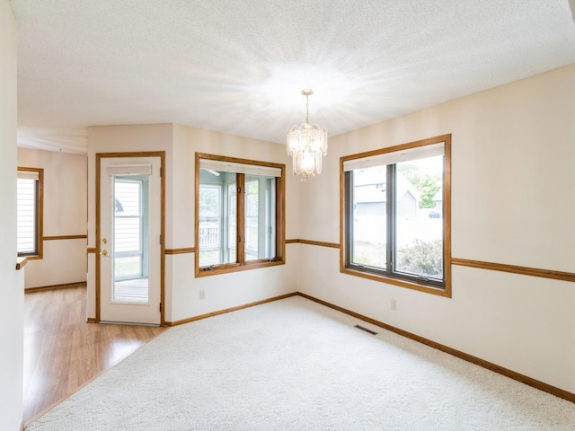 3721 Fletcher Blvd, Ames, IA 50010 - spare room featuring a chandelier, healthy amount of natural light, baseboards, and a textured ceiling