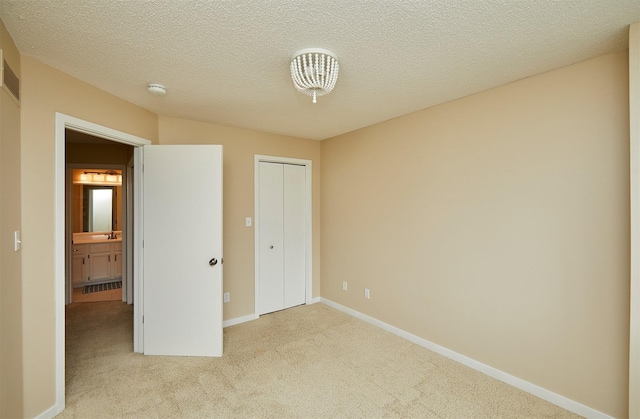 1050 68th St Unit 8, West Des Moines, IA 50266 - unfurnished bedroom featuring carpet flooring, a sink, baseboards, a textured ceiling, and a closet