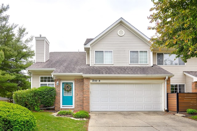 1050 68th St Unit 8, West Des Moines, IA 50266 - view of front facade featuring driveway, brick siding, a chimney, roof with shingles, and a garage