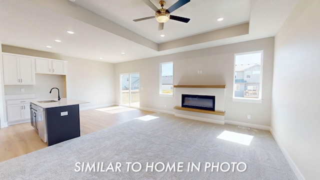 2540 E 50th Ct, Des Moines, IA 50317 - kitchen with a sink, a glass covered fireplace, white cabinets, a center island with sink, and baseboards