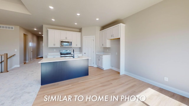 2540 E 50th Ct, Des Moines, IA 50317 - kitchen featuring stainless steel appliances, white cabinetry, a kitchen island with sink, baseboards, and recessed lighting