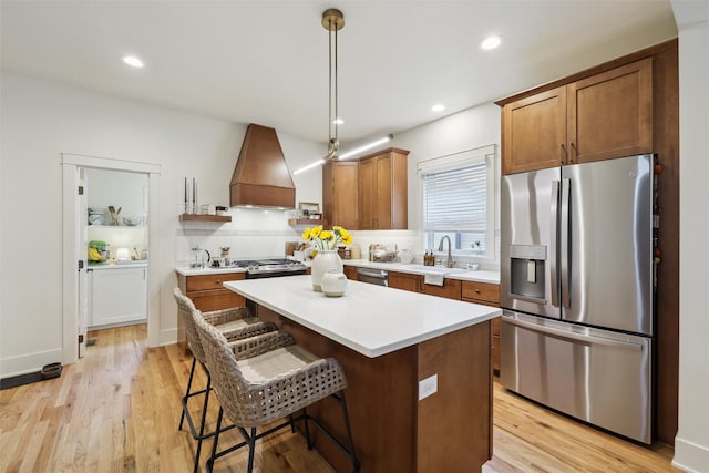 1107 24th St, Des Moines, IA 50311 - kitchen with stainless steel appliances, custom range hood, a sink, a kitchen island, and light countertops