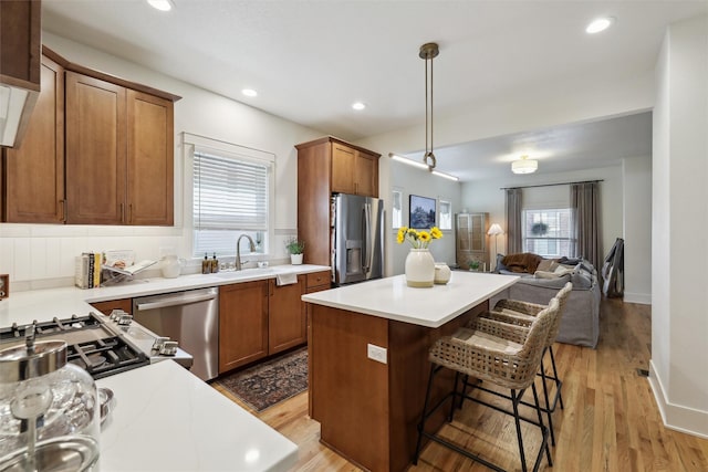 1107 24th St, Des Moines, IA 50311 - kitchen featuring stainless steel appliances, open floor plan, a sink, a center island, and brown cabinetry