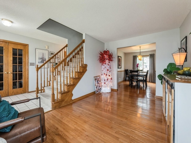 2190 NW 147th St, Clive, IA 50325 - living area featuring light wood-type flooring, stairs, a textured ceiling, and baseboards