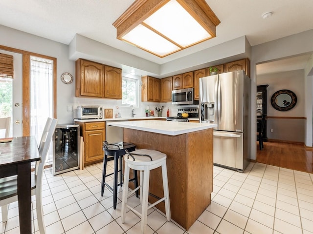2190 NW 147th St, Clive, IA 50325 - kitchen featuring appliances with stainless steel finishes, light countertops, a kitchen island, light tile patterned flooring, and a kitchen bar