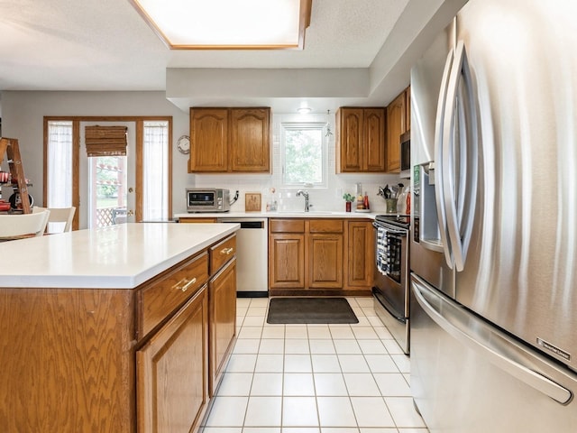 2190 NW 147th St, Clive, IA 50325 - kitchen with stainless steel appliances, brown cabinetry, and light countertops