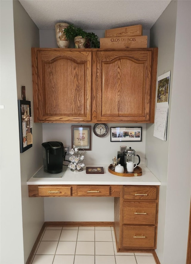 2190 NW 147th St, Clive, IA 50325 - kitchen with built in study area, brown cabinetry, light countertops, and a textured ceiling
