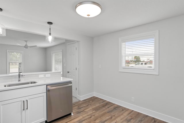 205 NW 51st Pl, Des Moines, IA 50313 - kitchen with stainless steel dishwasher, a sink, white cabinets, light wood-type flooring, and baseboards