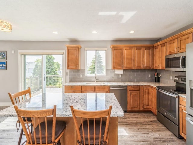 900 SE Woodbine Dr, Grimes, IA 50111 - kitchen featuring stainless steel appliances, a sink, light wood-style floors, backsplash, and a breakfast bar