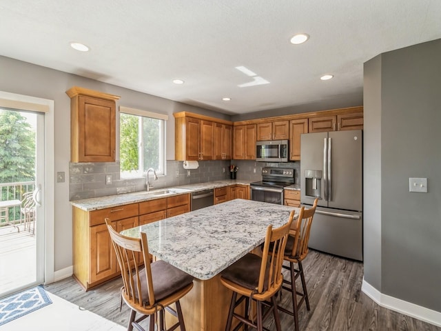 900 SE Woodbine Dr, Grimes, IA 50111 - kitchen with appliances with stainless steel finishes, a sink, backsplash, a breakfast bar, and recessed lighting