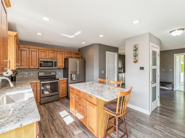 900 SE Woodbine Dr, Grimes, IA 50111 - kitchen with appliances with stainless steel finishes, a sink, dark wood-type flooring, a kitchen bar, and recessed lighting