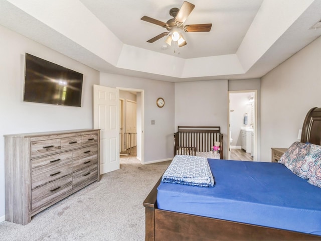 900 SE Woodbine Dr, Grimes, IA 50111 - bedroom featuring a raised ceiling, light carpet, baseboards, connected bathroom, and a ceiling fan