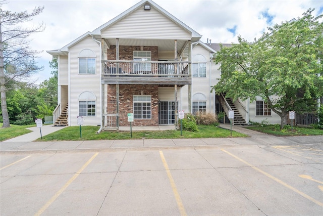 2433 Patricia Dr Unit 24, Urbandale, IA 50322 - view of front of home featuring stairway, a balcony, brick siding, uncovered parking, and a front yard