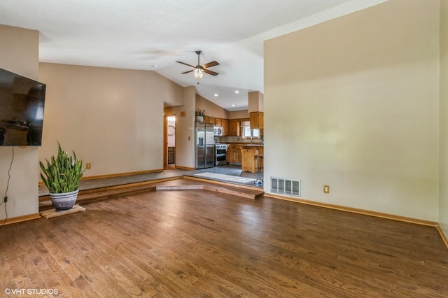 4685 E Broadway Ave, Des Moines, IA 50317 - unfurnished living room featuring wood finished floors, ceiling fan, baseboards, lofted ceiling, and a sink