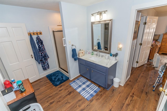 620 W Filmore St, Winterset, IA 50273 - full bath with wood finished floors, vanity, a shower stall, and baseboards