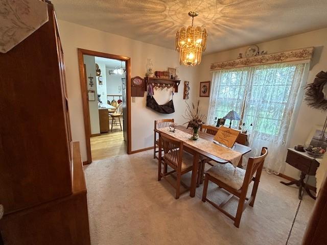 1102 S Broadway St, Toledo, IA 52342 - dining room featuring a chandelier, light colored carpet, and baseboards