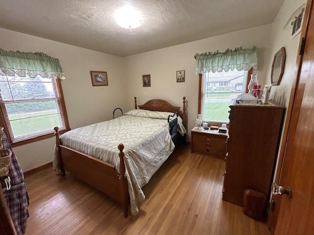 1102 S Broadway St, Toledo, IA 52342 - bedroom featuring wood finished floors and a textured ceiling