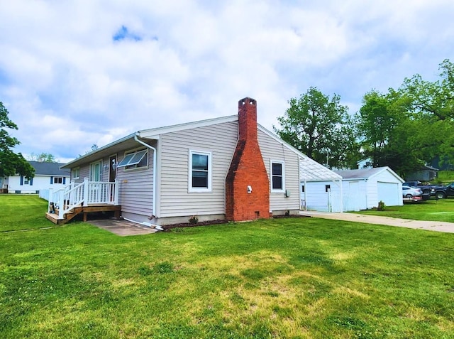 1420 Court Ave, Chariton, IA 50049 - view of home's exterior featuring a chimney, a yard, an outbuilding, and driveway