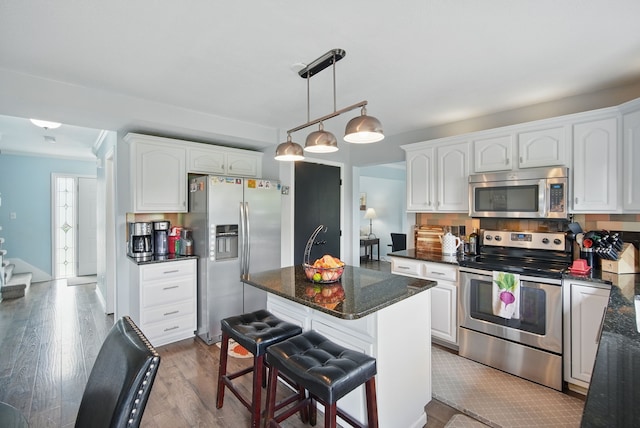 6173 Pommel Pl, West Des Moines, IA 50266 - kitchen with stainless steel appliances, white cabinetry, wood finished floors, and a kitchen island