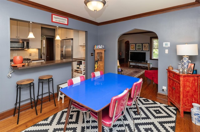 2118 34th St, Des Moines, IA 50310 - dining area featuring arched walkways, ornamental molding, and light wood finished floors