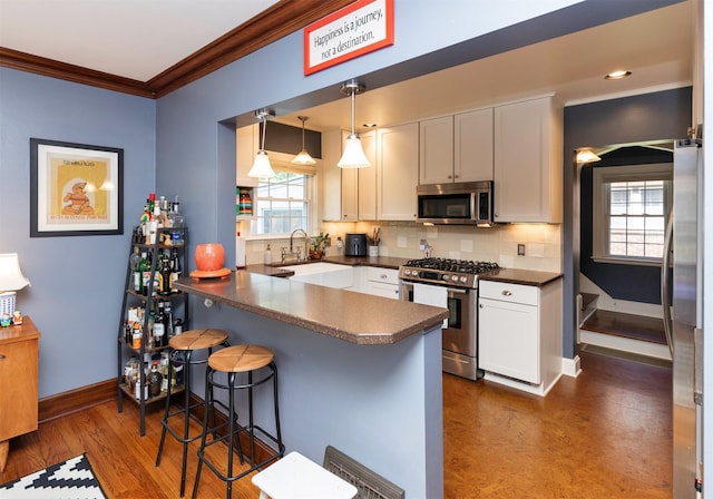 2118 34th St, Des Moines, IA 50310 - kitchen with stainless steel appliances, dark countertops, a sink, crown molding, and a peninsula