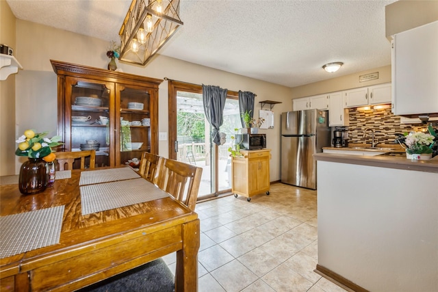 1903 W 5th Ave, Indianola, IA 50125 - kitchen featuring stainless steel appliances, white cabinets, a textured ceiling, tasteful backsplash, and light tile patterned flooring