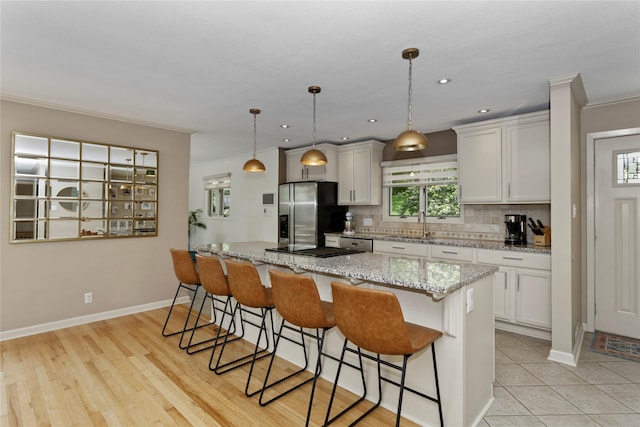 2740 Forest Dr, Des Moines, IA 50312 - kitchen featuring stainless steel fridge, a kitchen bar, tasteful backsplash, ornamental molding, and a sink