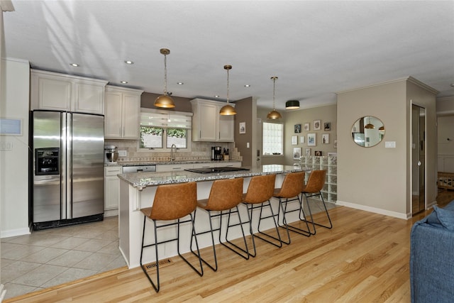 2740 Forest Dr, Des Moines, IA 50312 - kitchen with stainless steel appliances, a breakfast bar, tasteful backsplash, baseboards, and crown molding