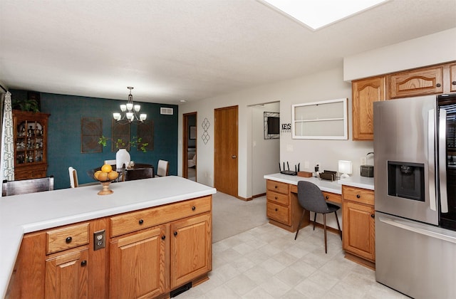 310 NE Meadowlark Ln, Waukee, IA 50263 - kitchen featuring stainless steel refrigerator with ice dispenser, light countertops, a chandelier, built in desk, and brown cabinetry
