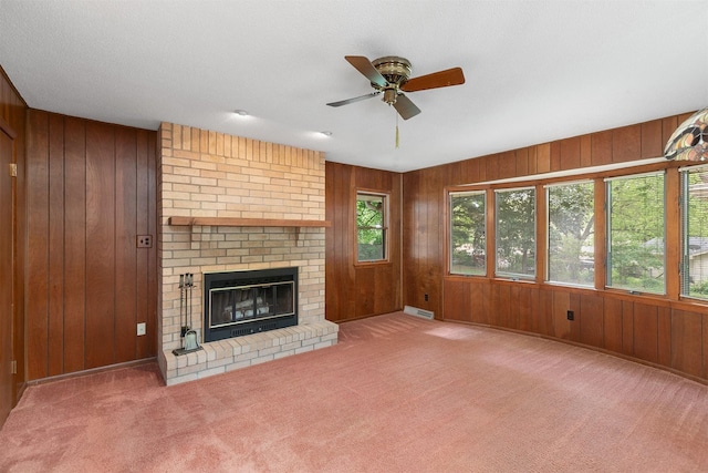 2700 Dosh Rd, Des Moines, IA 50310 - unfurnished living room with wood walls, ceiling fan, a brick fireplace, and carpet flooring
