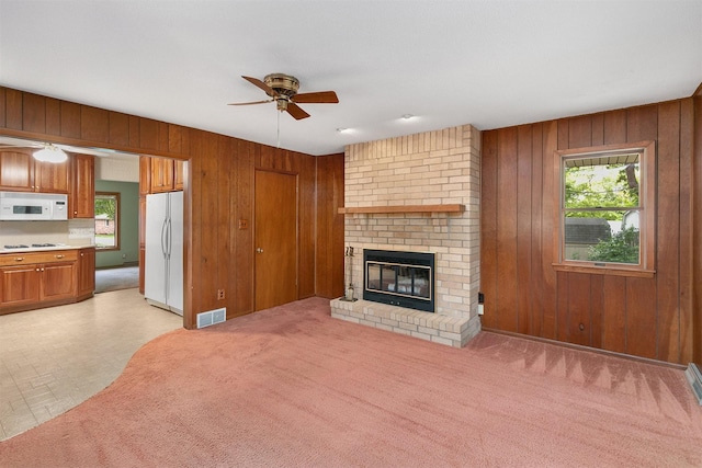 2700 Dosh Rd, Des Moines, IA 50310 - unfurnished living room featuring a ceiling fan, wooden walls, plenty of natural light, and a fireplace