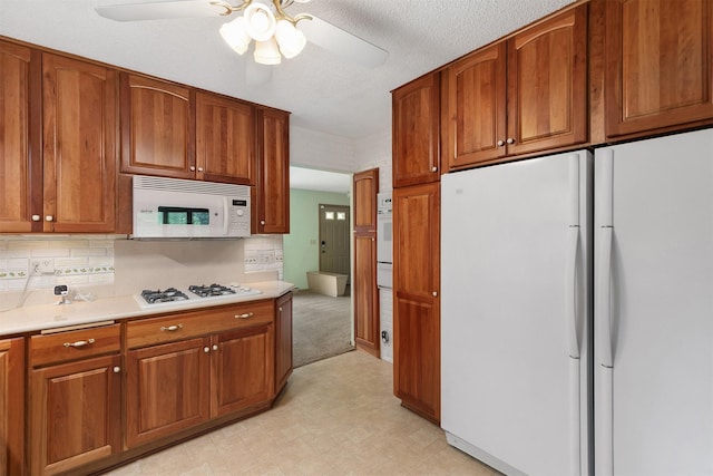 2700 Dosh Rd, Des Moines, IA 50310 - kitchen featuring white appliances, brown cabinetry, light countertops, and ceiling fan