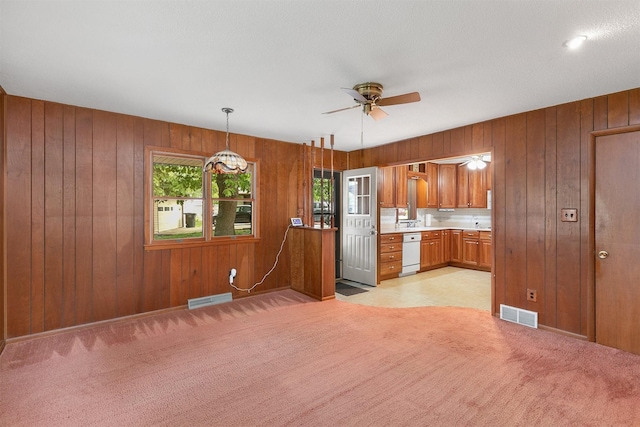 2700 Dosh Rd, Des Moines, IA 50310 - kitchen featuring dishwasher, brown cabinetry, wood walls, light countertops, and a ceiling fan