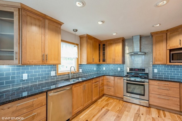 4337 Park Ct, Urbandale, IA 50322 - kitchen with appliances with stainless steel finishes, a sink, wall chimney range hood, light wood-type flooring, and dark stone counters