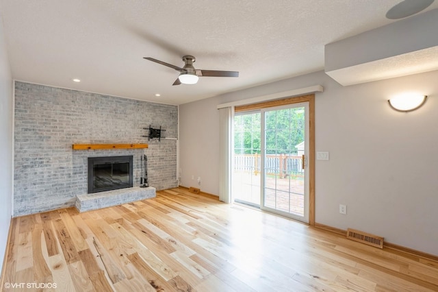 4337 Park Ct, Urbandale, IA 50322 - unfurnished living room with wood finished floors, ceiling fan, a brick fireplace, recessed lighting, and a textured ceiling