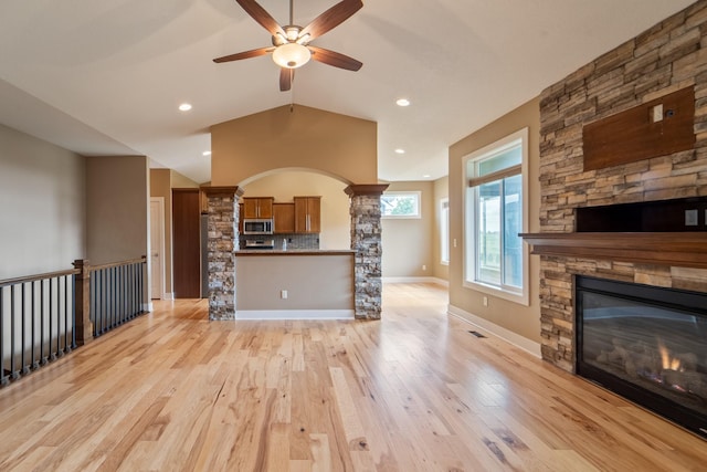 916 NE Silkwood St, Grimes, IA 50111 - unfurnished living room with a fireplace, a ceiling fan, light wood-type flooring, vaulted ceiling, and decorative columns