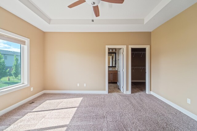 916 NE Silkwood St, Grimes, IA 50111 - unfurnished bedroom with a raised ceiling, carpet floors, a spacious closet, and a ceiling fan