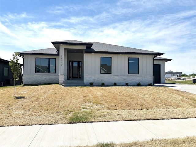16332 Northpark Dr, Urbandale, IA 50323 - view of front of house with board and batten siding, roof with shingles, stone siding, and central air condition unit