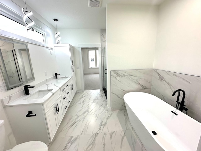16332 Northpark Dr, Urbandale, IA 50323 - full bath with marble look tile flooring, a freestanding tub, plenty of natural light, double vanity, and tile walls